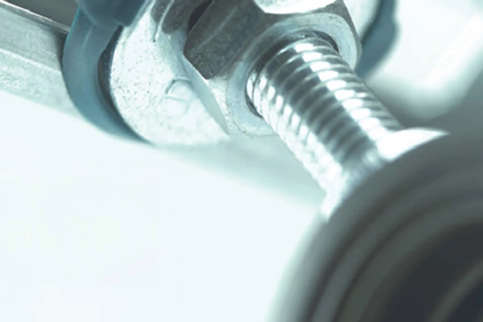 Close-up of a metal bolt and nut with threaded shaft in cool blue-tinted lighting.