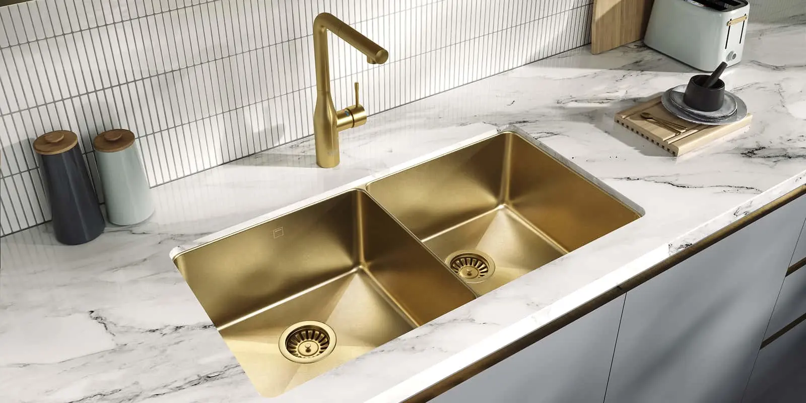 Modern kitchen with gold double sink and matching faucet in white marble countertop, with storage containers nearby.