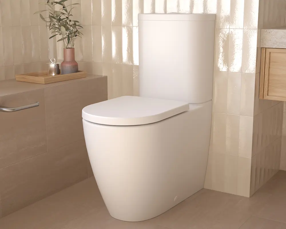Modern white toilet in a beige bathroom with decorative plant in vase on wooden tray nearby.