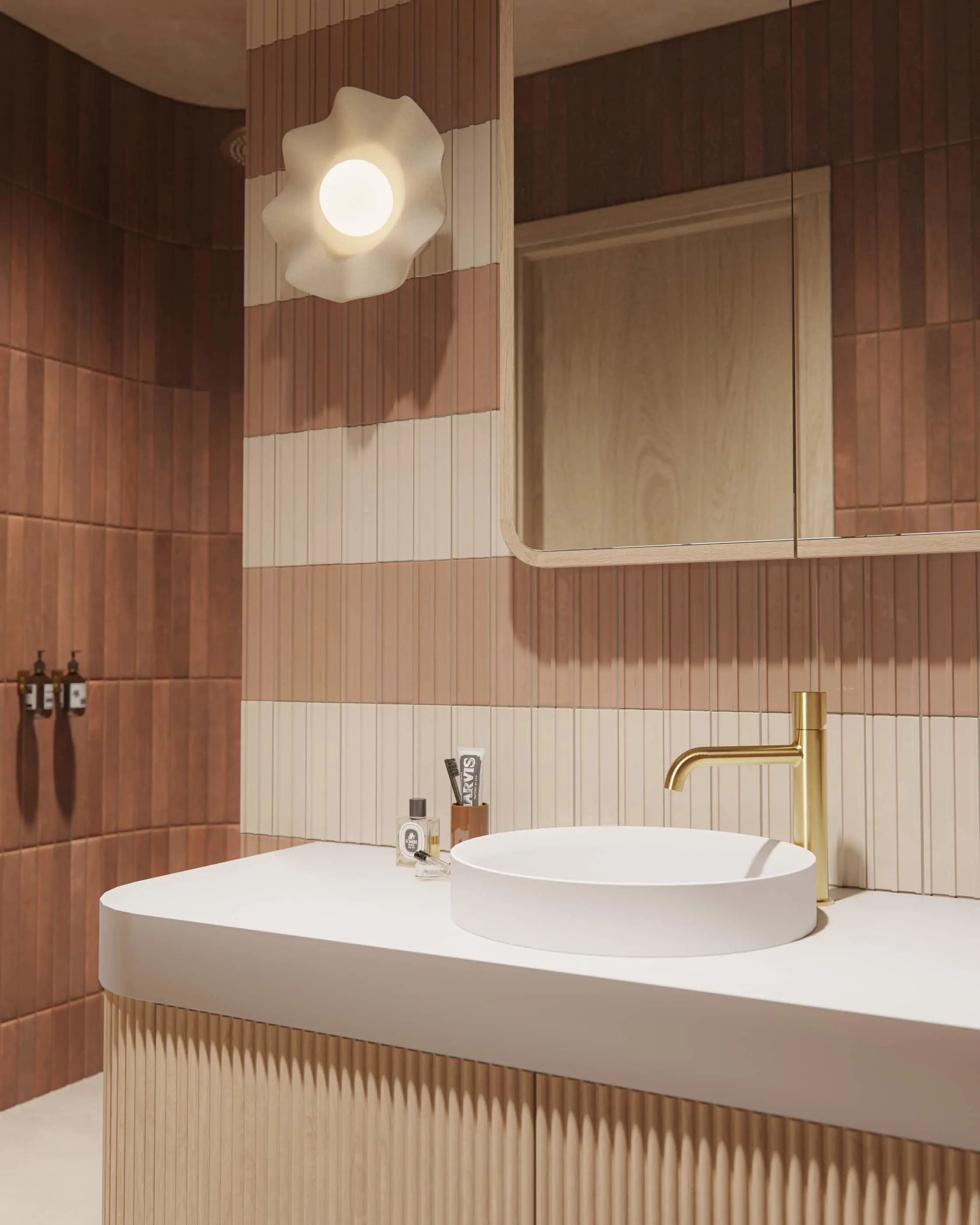 Modern bathroom with terracotta and cream tiled walls, white sink, brass faucet, and flower-shaped wall light.