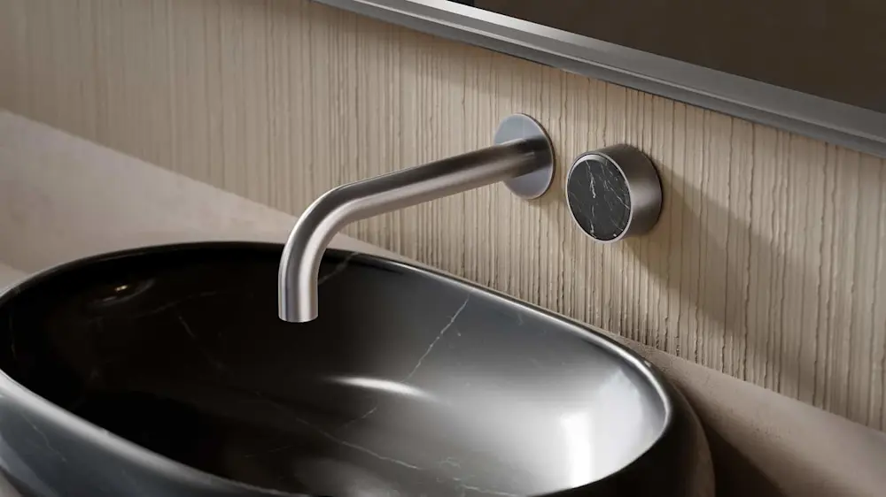 Modern bathroom sink with curved stainless steel wall-mounted faucet and black marble control knob on light wood wall.