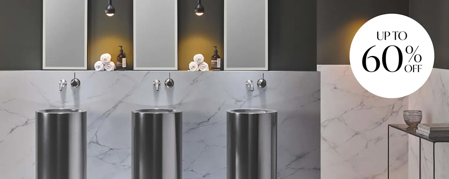 Modern bathroom with three metal pedestal sinks against marble wall, lit alcoves with towels, and 60% off promotion.