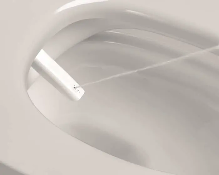 Close-up of a white ceramic toilet bowl interior showing the rim and water jet nozzle.