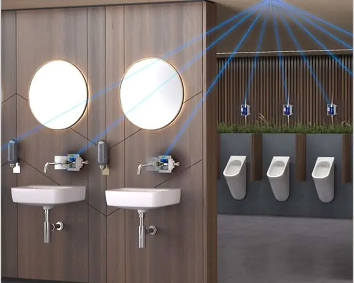 Modern bathroom with two sinks, round mirrors, and three urinals with blue sensor beams showing touchless technology.