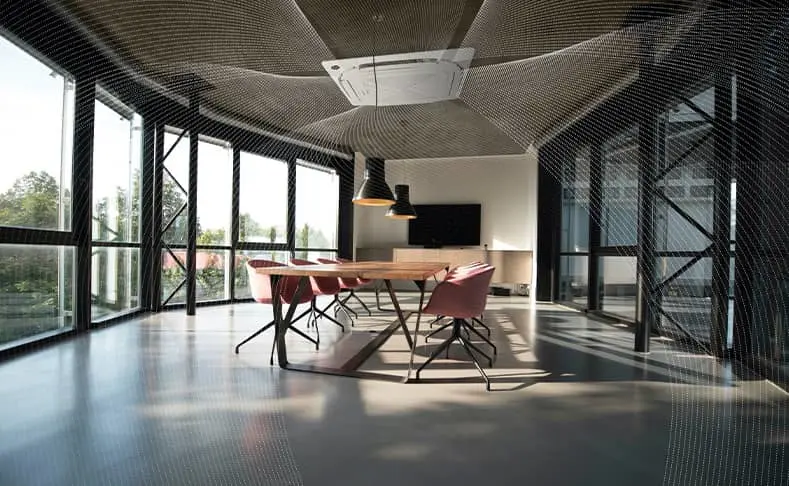 Modern conference room with wooden table, pink chairs, glass walls, and ceiling-mounted air conditioning unit.