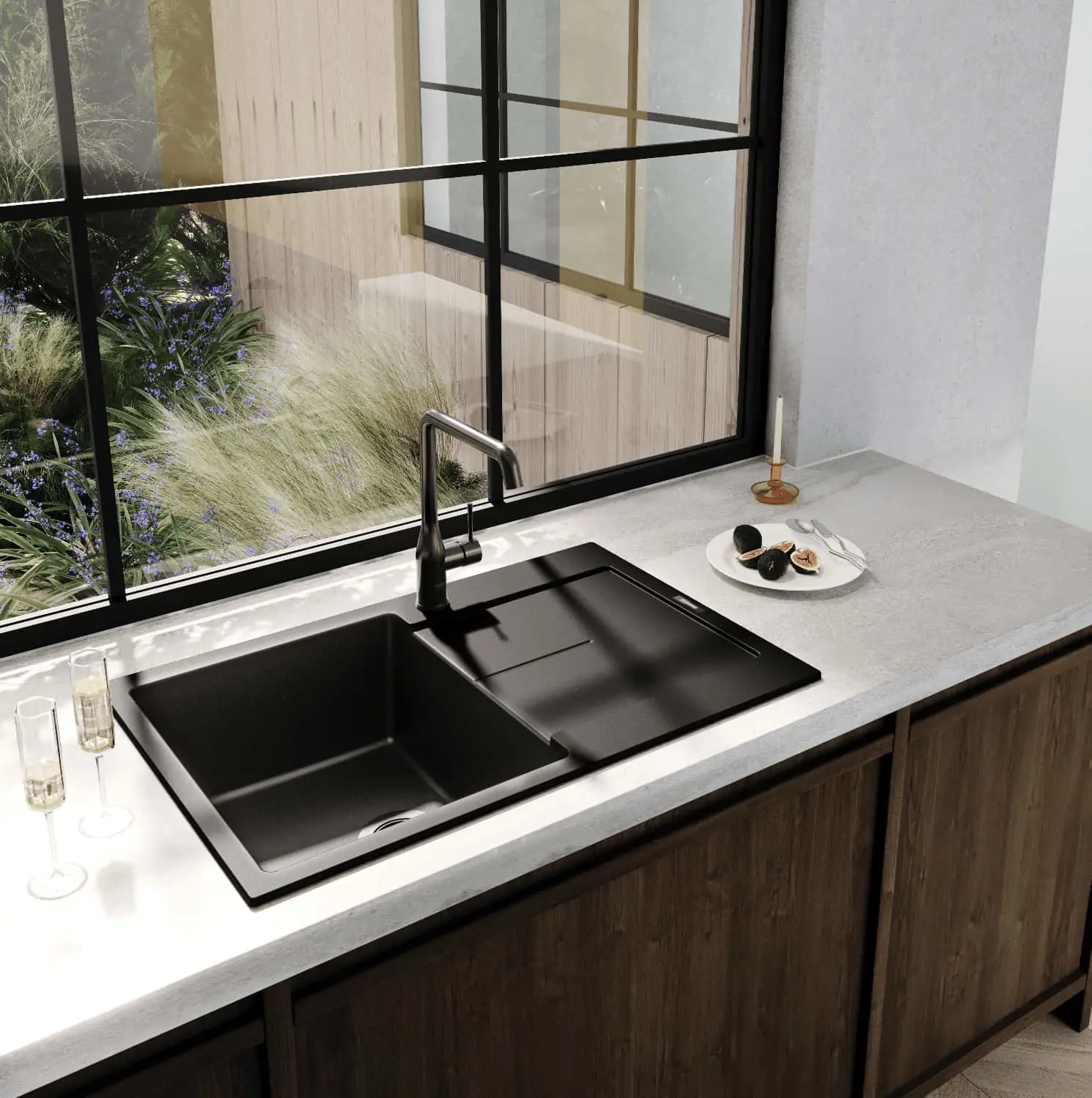 Modern black kitchen sink with faucet on gray countertop, window view of garden plants, plate with figs nearby.