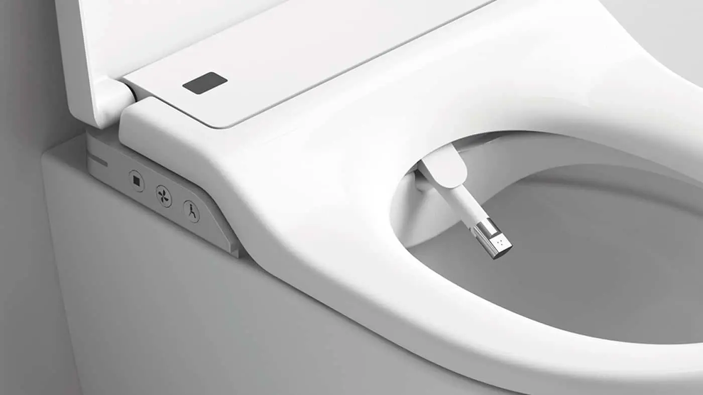 Close-up of a white electronic bidet toilet seat with control buttons and a retractable cleaning nozzle.