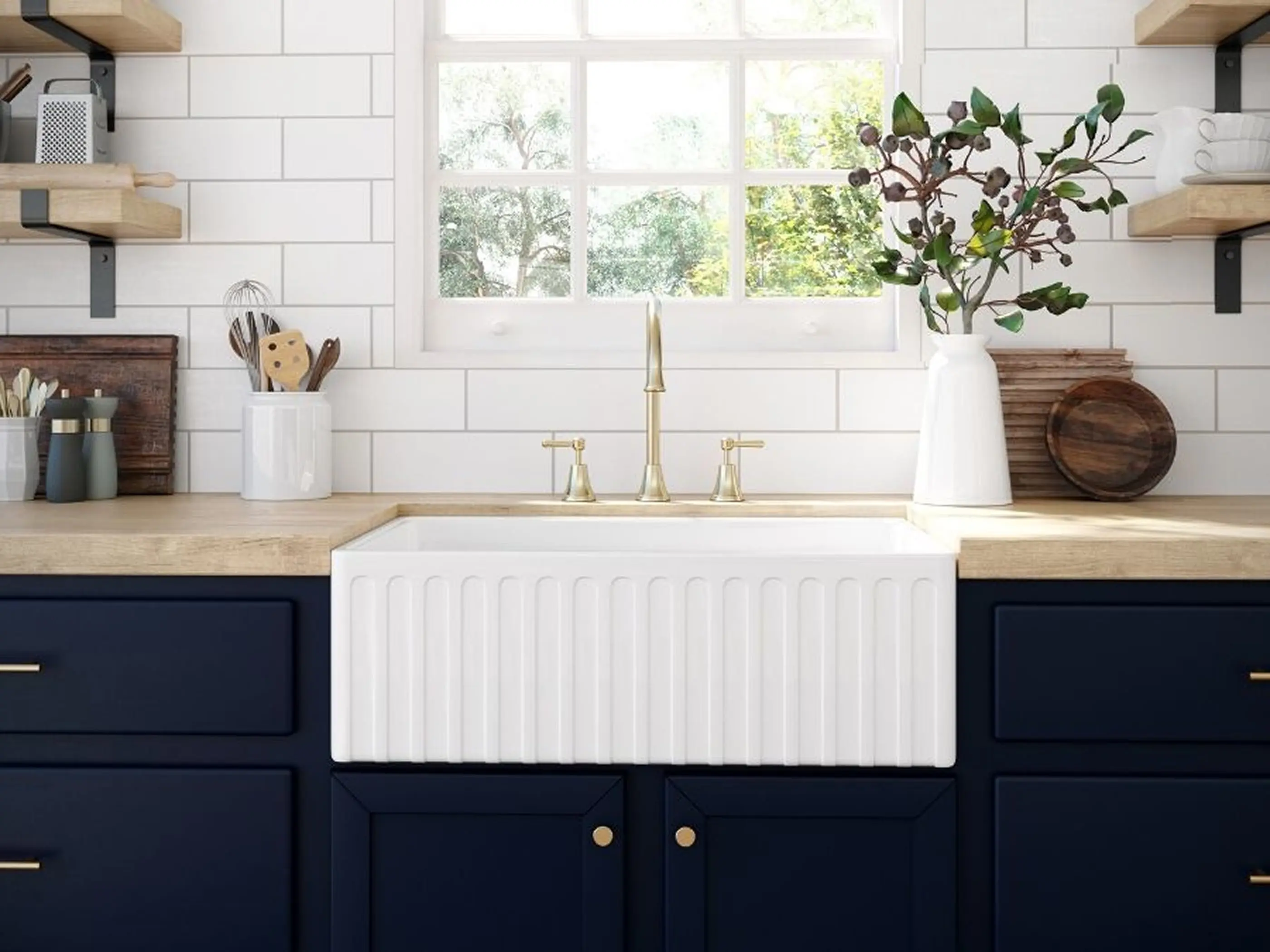 Modern farmhouse kitchen with white apron sink, brass faucet, navy cabinets, wooden countertops, and window above sink.