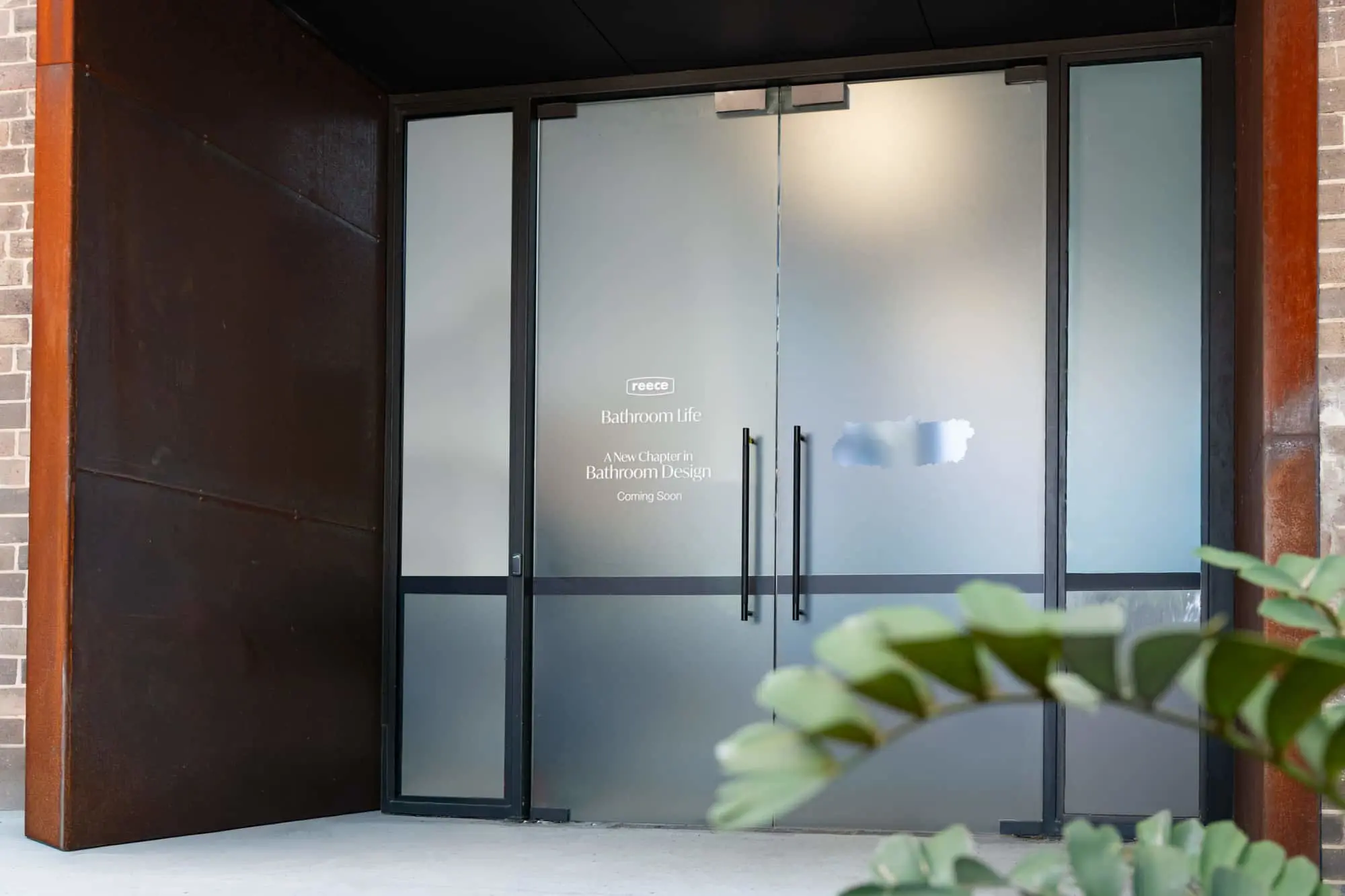 Frosted glass doors with "Reece Bathroom Life" signage announcing "A New Chapter in Bathroom Design Coming Soon"