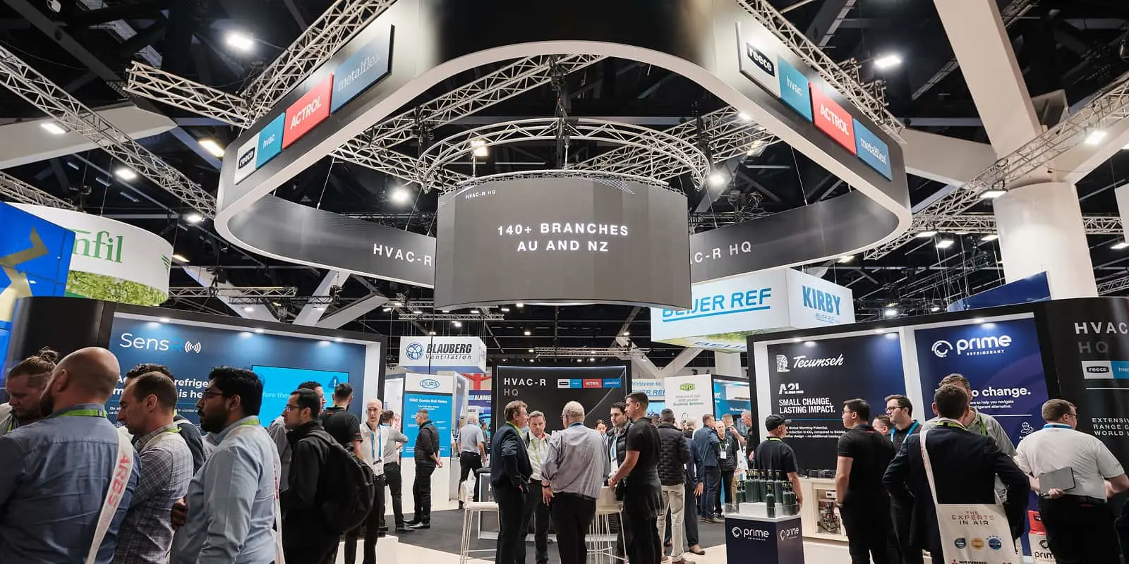 HVAC-R trade show with circular overhead display showing "140+ BRANCHES AU AND NZ" and attendees browsing exhibition booths.
