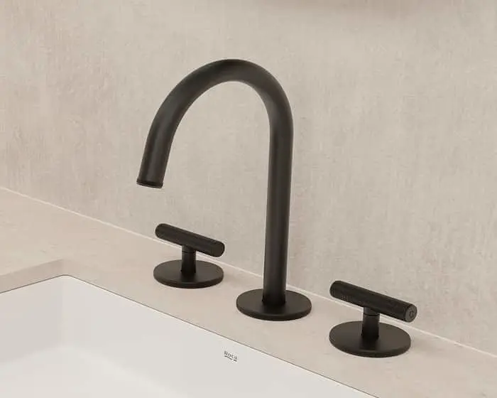 Modern matte black bathroom faucet with curved spout and two separate handle controls mounted on a white sink.