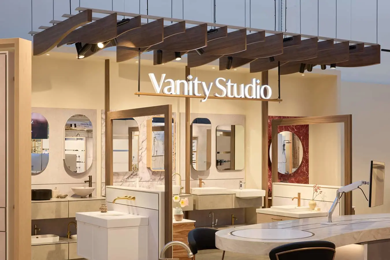 A showroom display labeled Vanity Studio featuring multiple bathroom vanity setups with sinks, faucets, and mirrors.