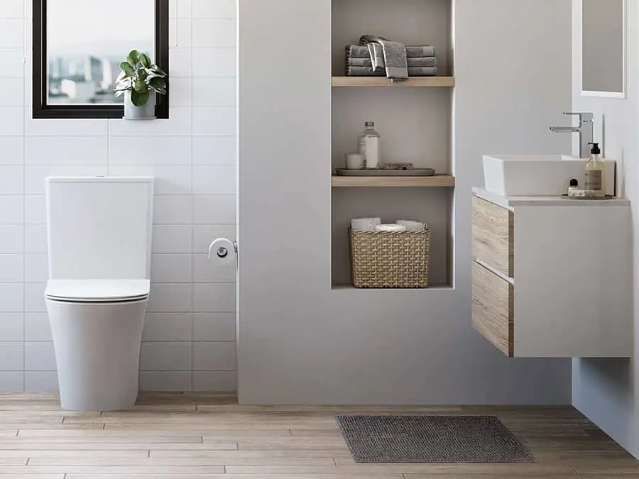 Modern bathroom with white toilet, wall-mounted sink, built-in shelving with towels and storage basket, and small plant.