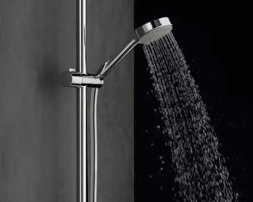 Chrome shower head with water flowing, mounted on a metal rail against a dark background.