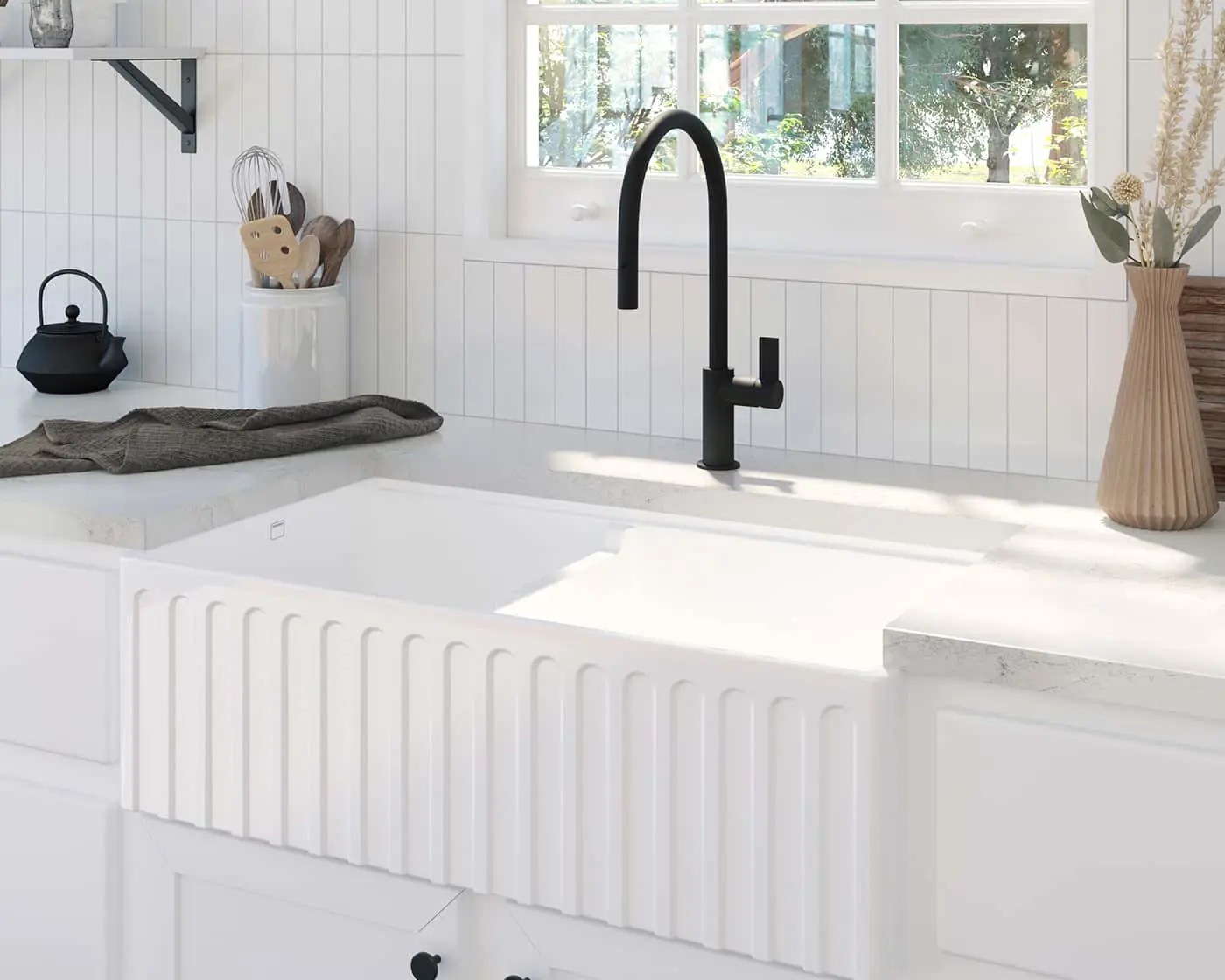 Modern white farmhouse kitchen with black faucet, apron sink, marble countertops, and window overlooking garden.