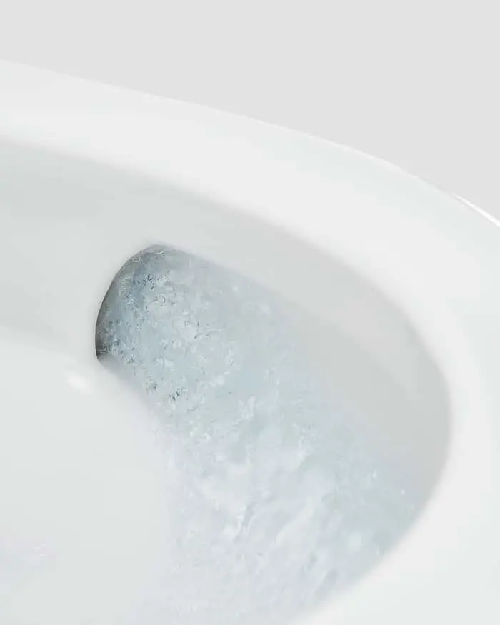 Water swirling in a white porcelain toilet bowl during flush cycle