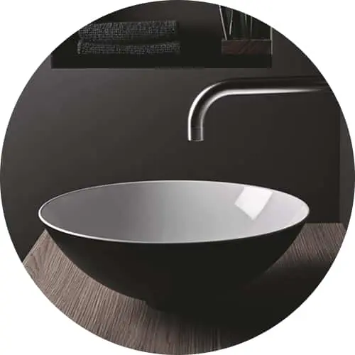 Modern black oval bathroom sink with chrome faucet mounted on wooden countertop, shown in circular frame.