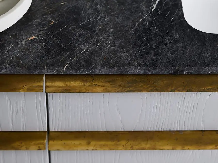 Black marble countertop with white sinks above wooden trim and white textured wall panels.