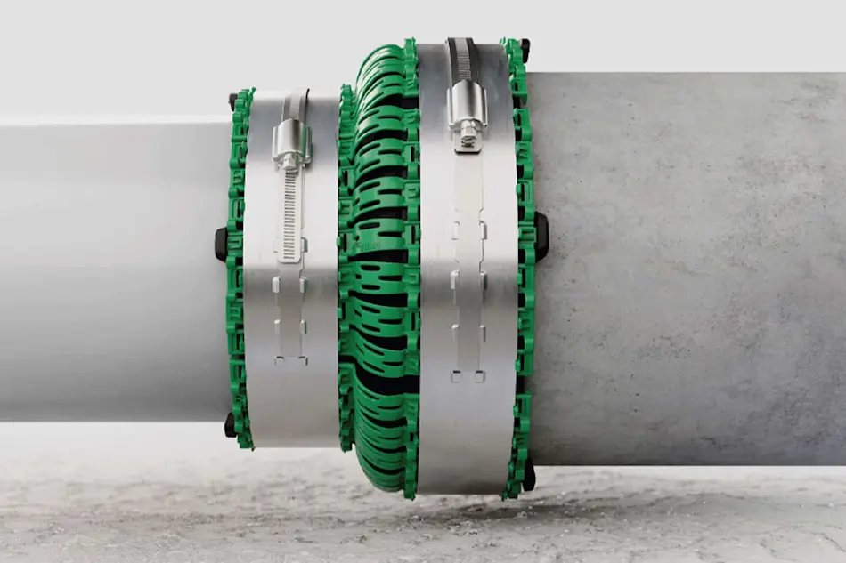 Industrial pipe clamps with green rubber inserts securing a gray pipe, mounted on concrete surface.