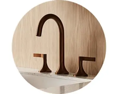 Modern bronze bathroom faucet with curved spout and two handles against light wood paneling