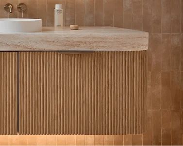 Modern bathroom vanity with stone countertop and vertical wooden slats against beige tiled wall.