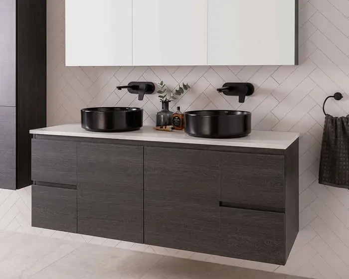 Modern bathroom vanity with dark wood cabinets, white countertop, two black vessel sinks, and wall-mounted black faucets.