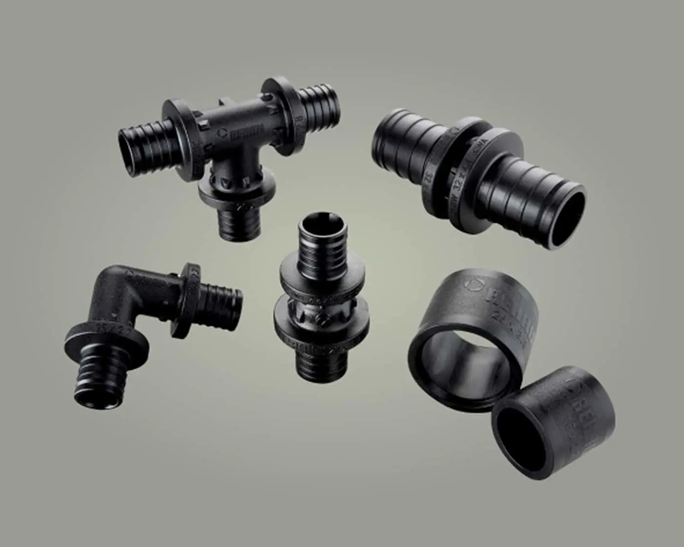 Black plastic plumbing fittings including T-joints, elbow connector, couplings, and reducer rings against a gray background.