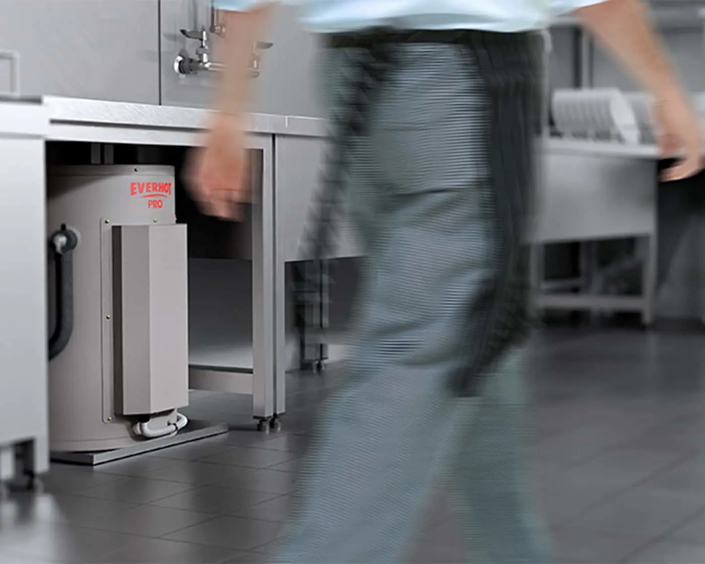 Blurred person walking past commercial kitchen equipment with an Everhot Pro appliance visible under counter.