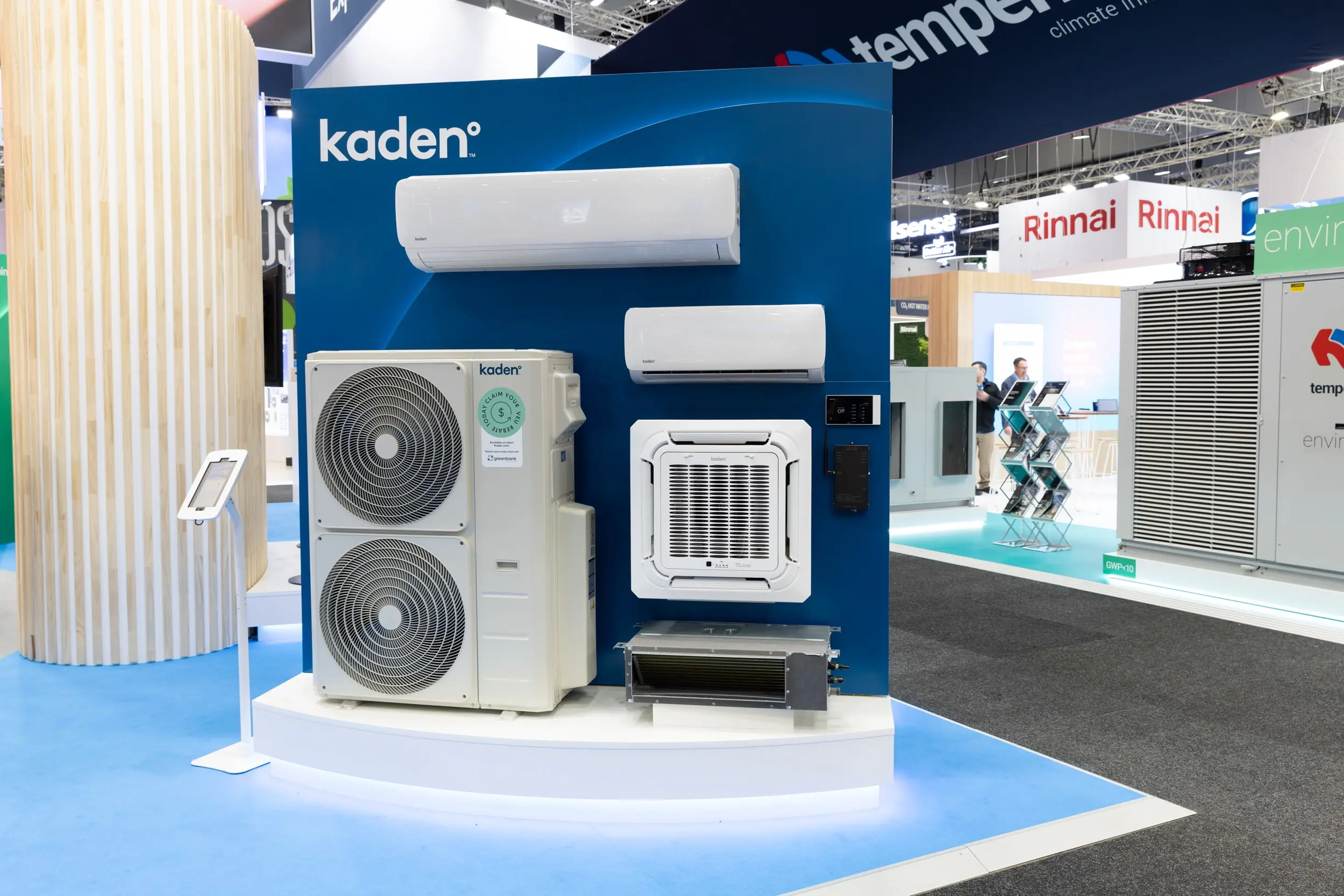 Kaden branded air conditioning units displayed at a trade show, including wall-split, cassette, and ducted units with an outdoor condenser.
