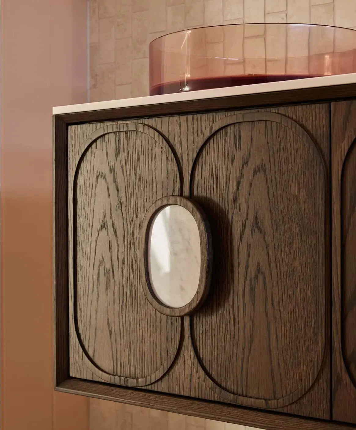 Modern bathroom details showing wooden cabinet with pink sink.