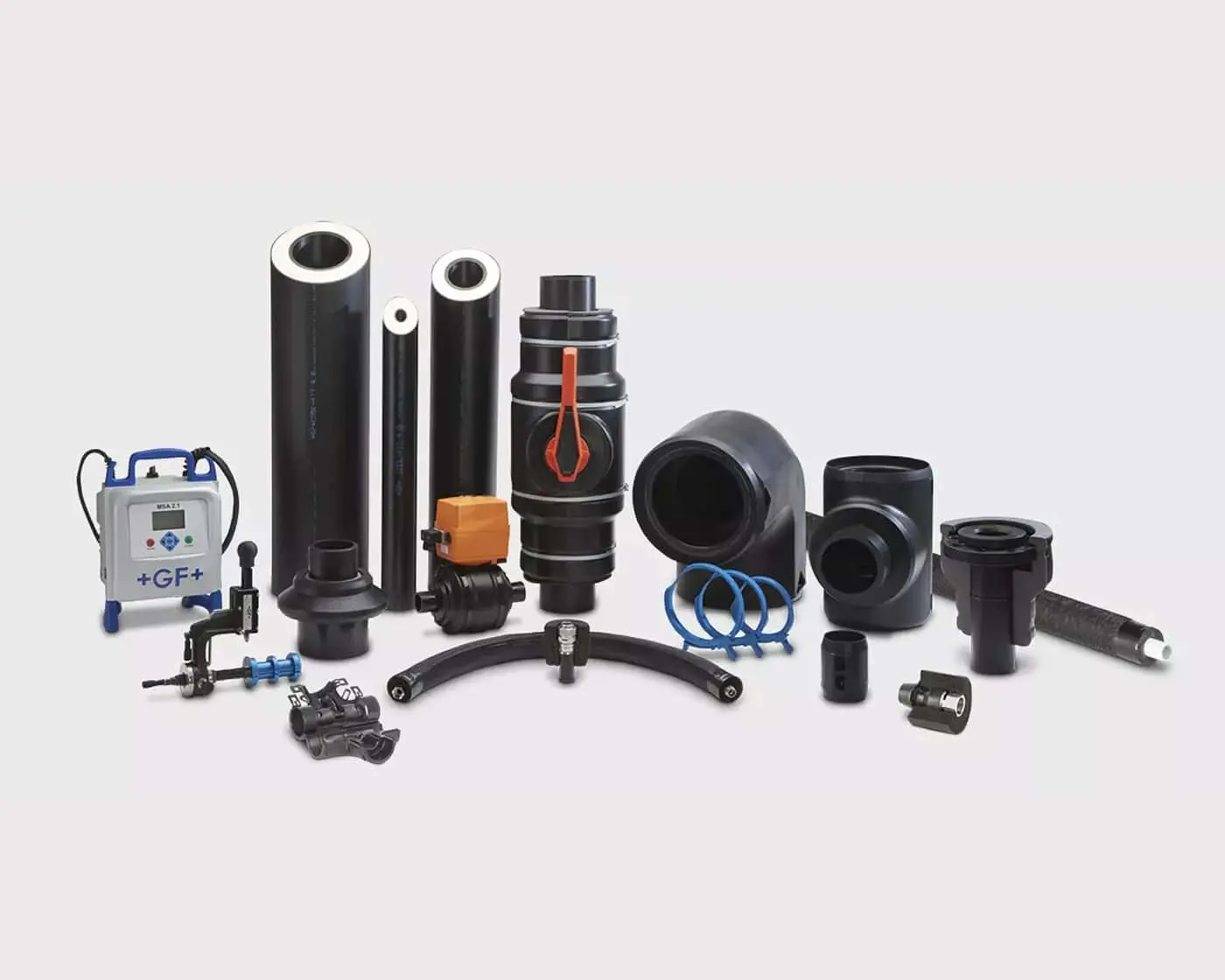 Collection of black industrial plumbing components including pipes, valves, fittings, and a small electronic control unit.