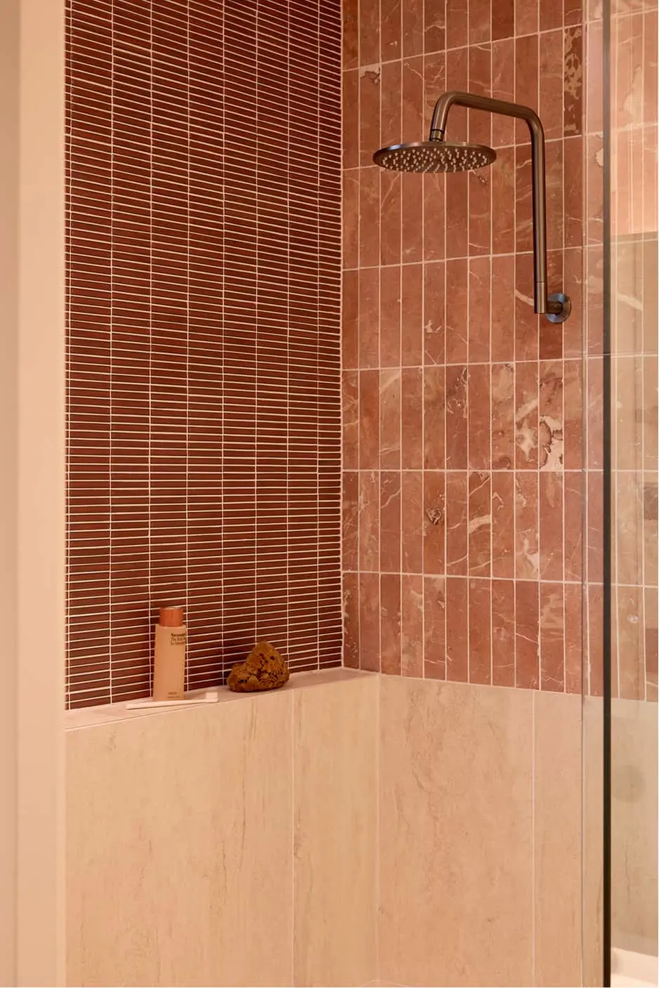 Modern shower with terracotta and cream tiles, bronze rainfall showerhead, and glass partition.