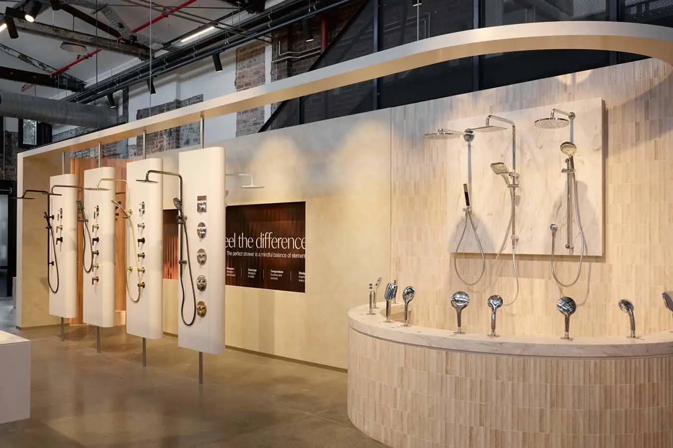 A showroom display of various shower systems and handheld showerheads mounted on light wood panels and a curved tiled counter.