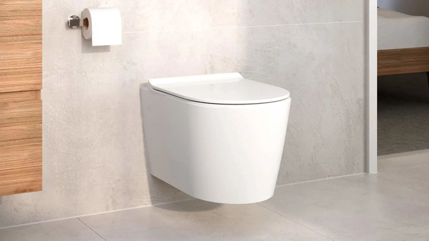 Modern wall-mounted white toilet with closed lid in a bathroom with light gray walls and wooden accents.