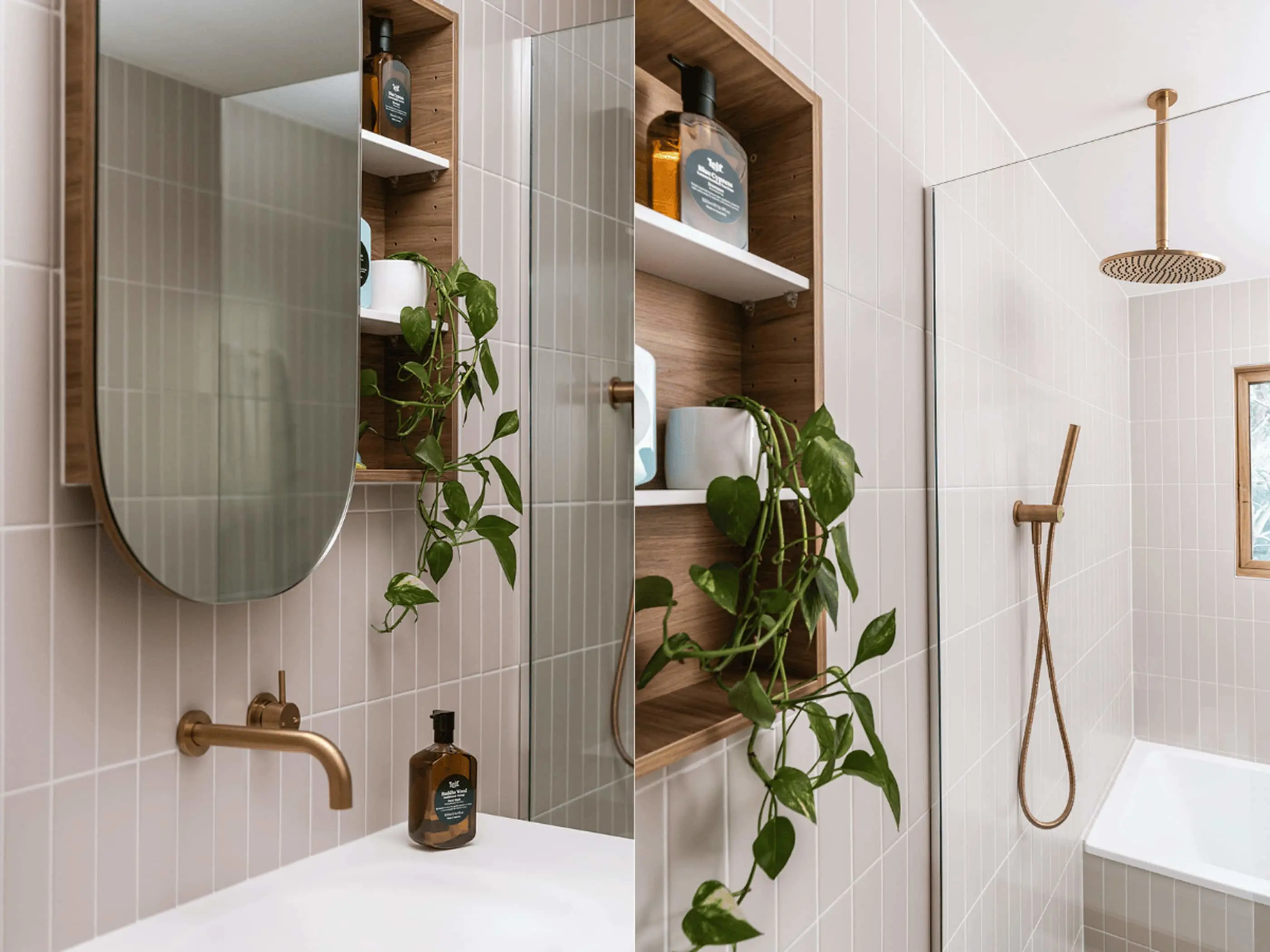 Modern bathroom with white tiles, wooden shelving, hanging plants, brass fixtures, and a rainfall shower head.