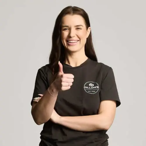 Person with long dark hair wearing a black t-shirt with a logo, giving thumbs up against light background.