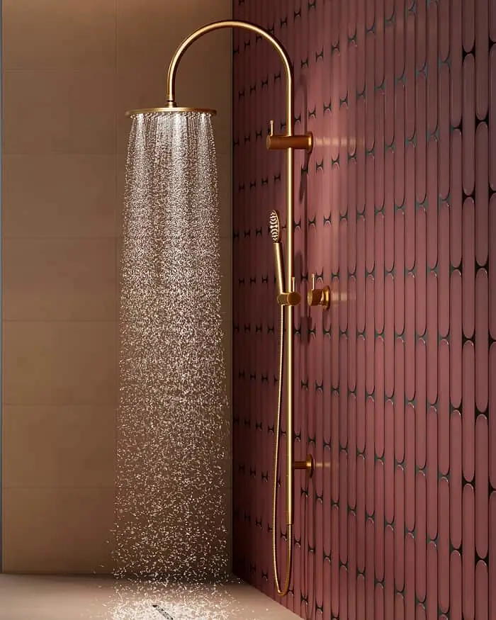 Gold shower system with overhead rain head running water, mounted against a corner with a dark red patterned tile wall.