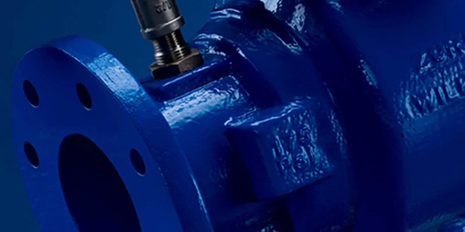 Close-up of blue industrial valve with metal bolt connection against dark blue background.