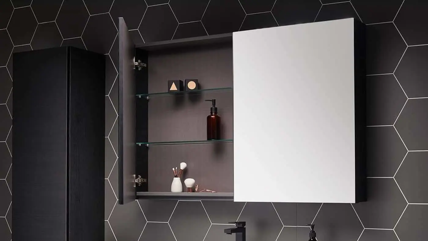 Modern bathroom cabinet with mirror door open showing glass shelves with toiletries against black hexagon tile wall.