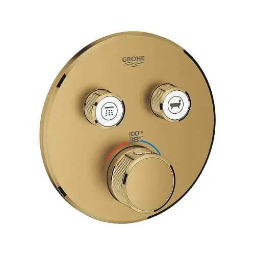 Gold GROHE shower control panel with temperature dial and two function buttons mounted on circular plate.