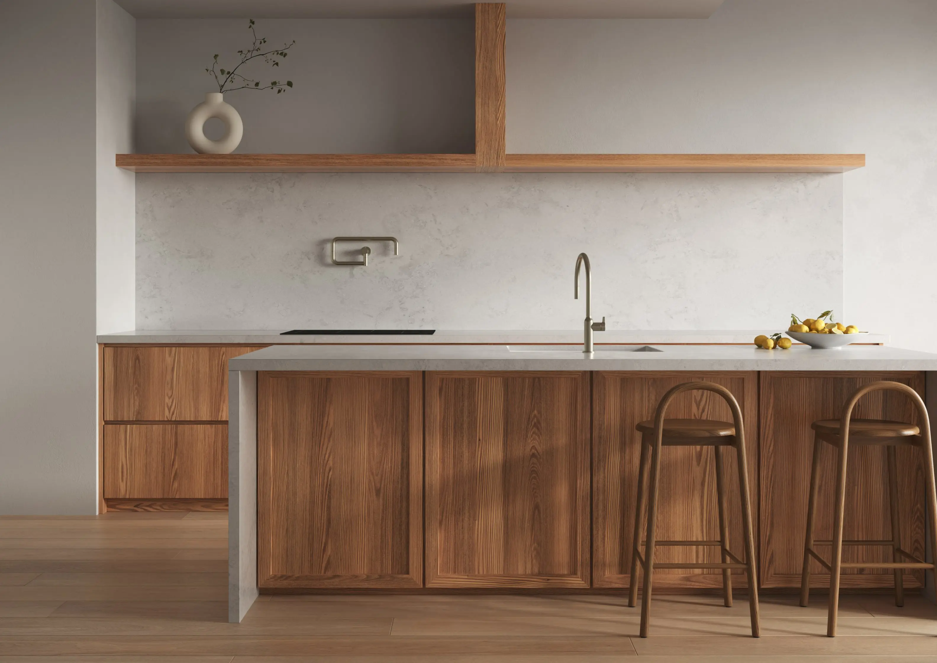 Kitchen with wood cabinets, light stone countertop island, two wooden bar stools, a sink, and a bowl of lemons on the counter.
