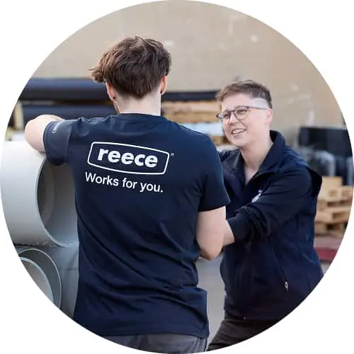 Two people in navy workwear talking, one wearing a shirt with "reece Works for you" text on the back.