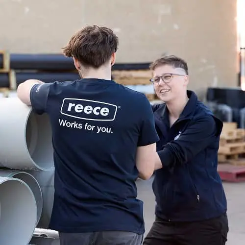 Two people in navy workwear talking, one wearing a shirt with "reece Works for you" text on the back.