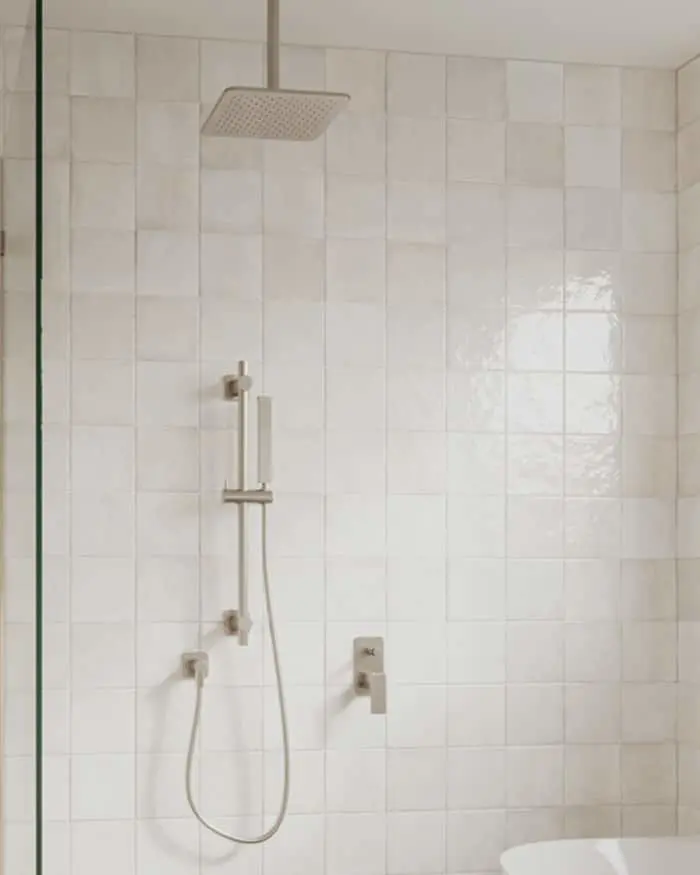 Modern shower with square rainfall showerhead, handheld sprayer, and cream-colored tile walls in a minimalist bathroom.