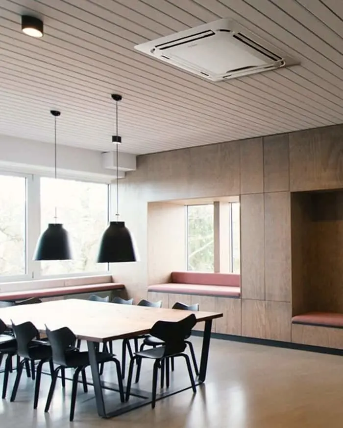 Modern dining area with wooden table, black chairs, pendant lights, ceiling air conditioner, and built-in seating nook.