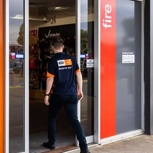 Person in Reece uniform entering a store with red signage and glass doors.