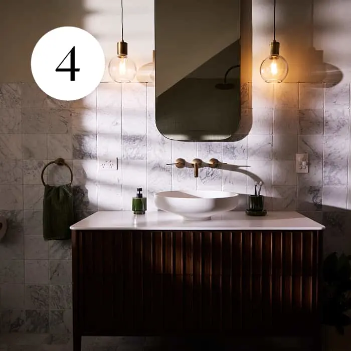 Bathroom vanity with dark wood cabinet, white basin, brass taps, marble tiles, pendant lights, and a mirror. Number 4 overlay.