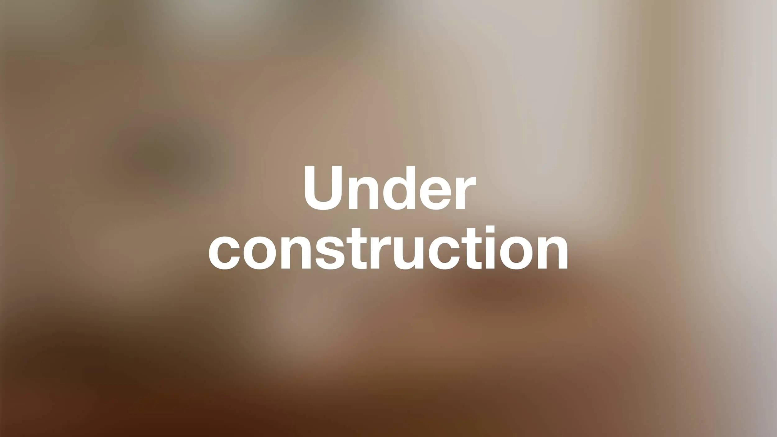 White bold text reading "Under construction" on a blurred brown and beige background.