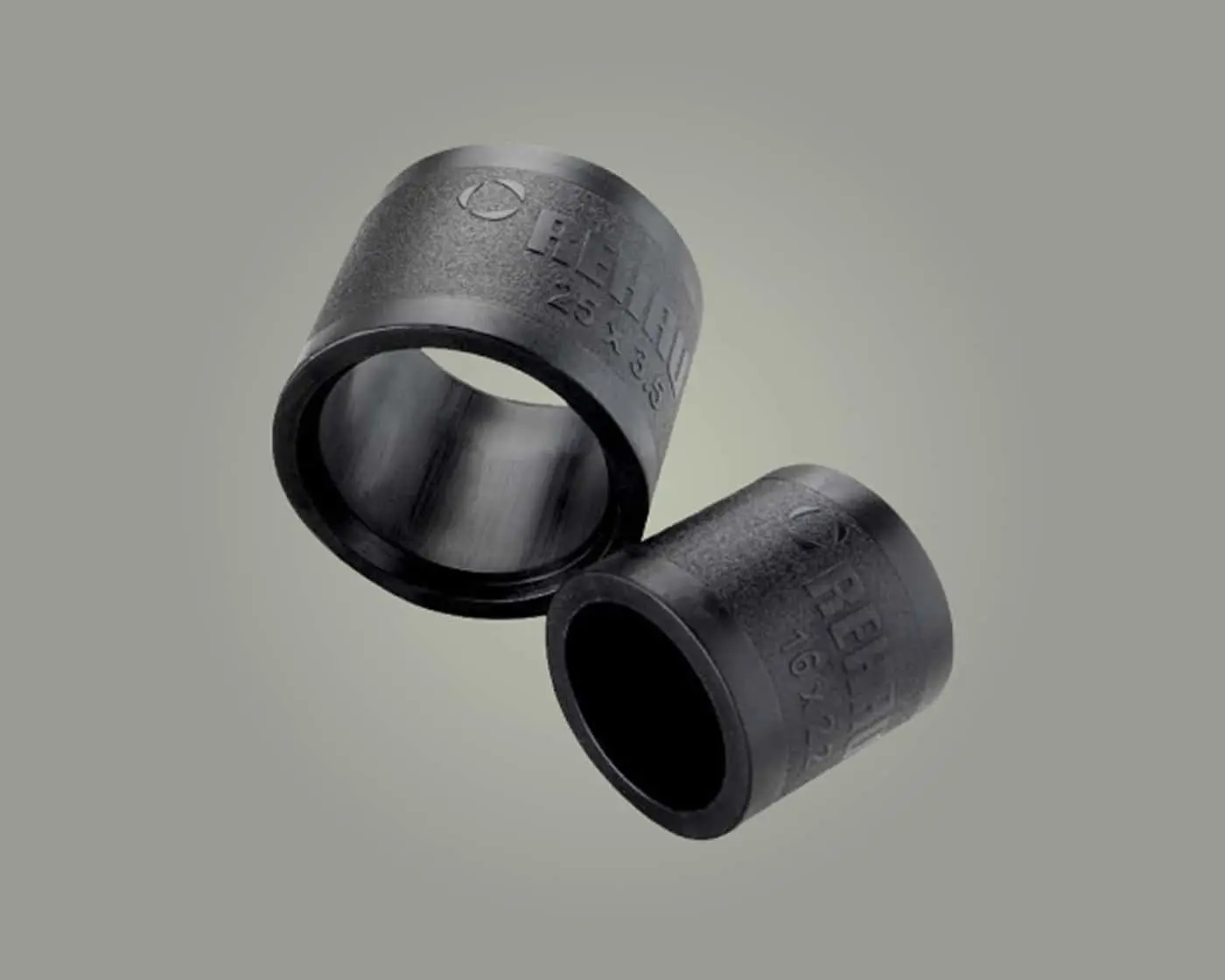 Two dark metal pipe fittings with embossed text and measurements against a light gray background.