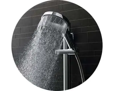 Modern shower head spraying water against black tile wall in a circular framed image.